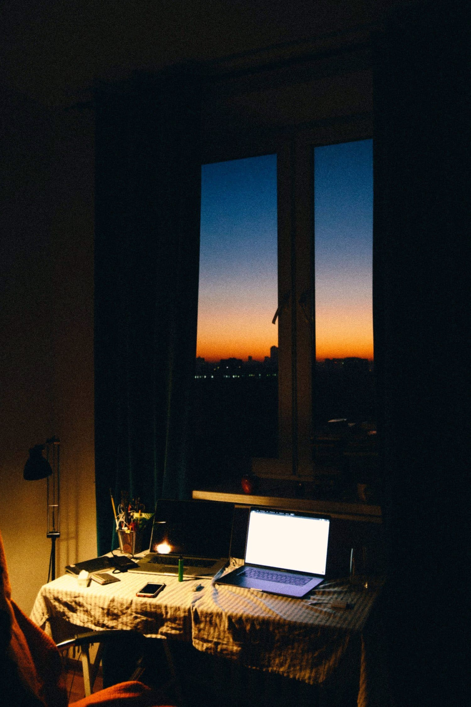 A dim room before dawn, a single small screen glowing by the window
